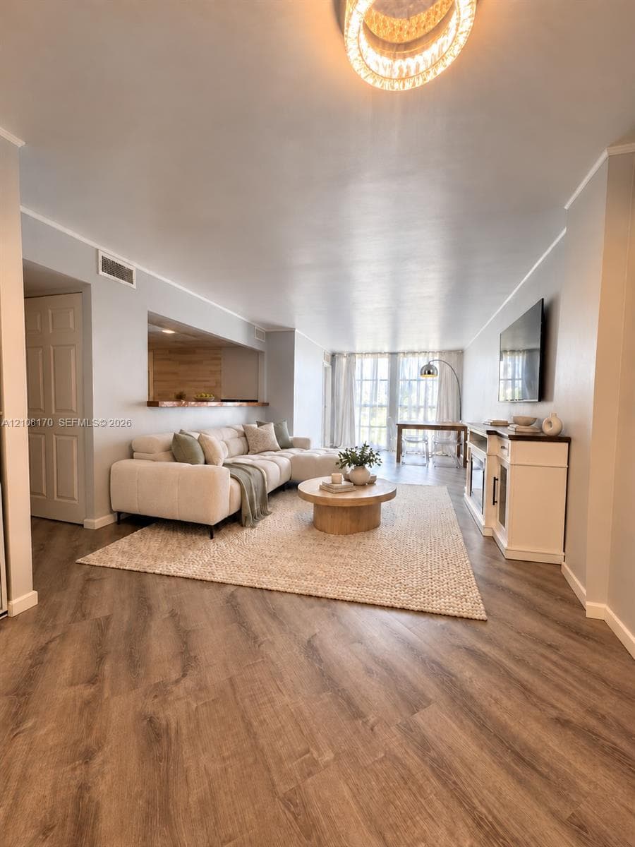 Living area featuring wood-finish flooring, bar, floor-to-ceiling windows and a circular drum chandelier