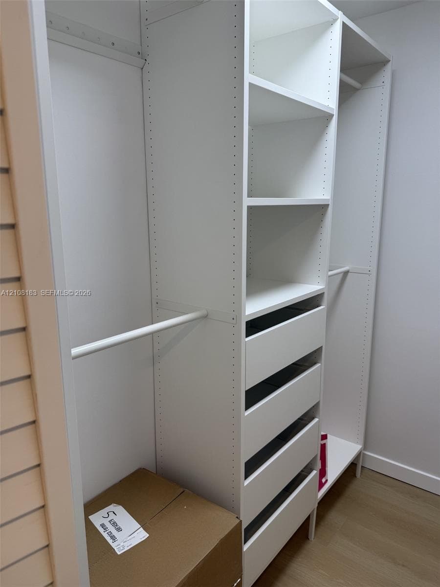 Built-in closet system featuring white modular cabinetry, adjustable shelving, integrated hanging rods, and a five-drawer unit