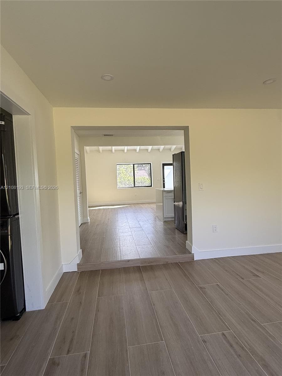 Interior space featuring wood-finish tile flooring, recessed lighting, and a multi-level floor plan with an exposed beam ceiling