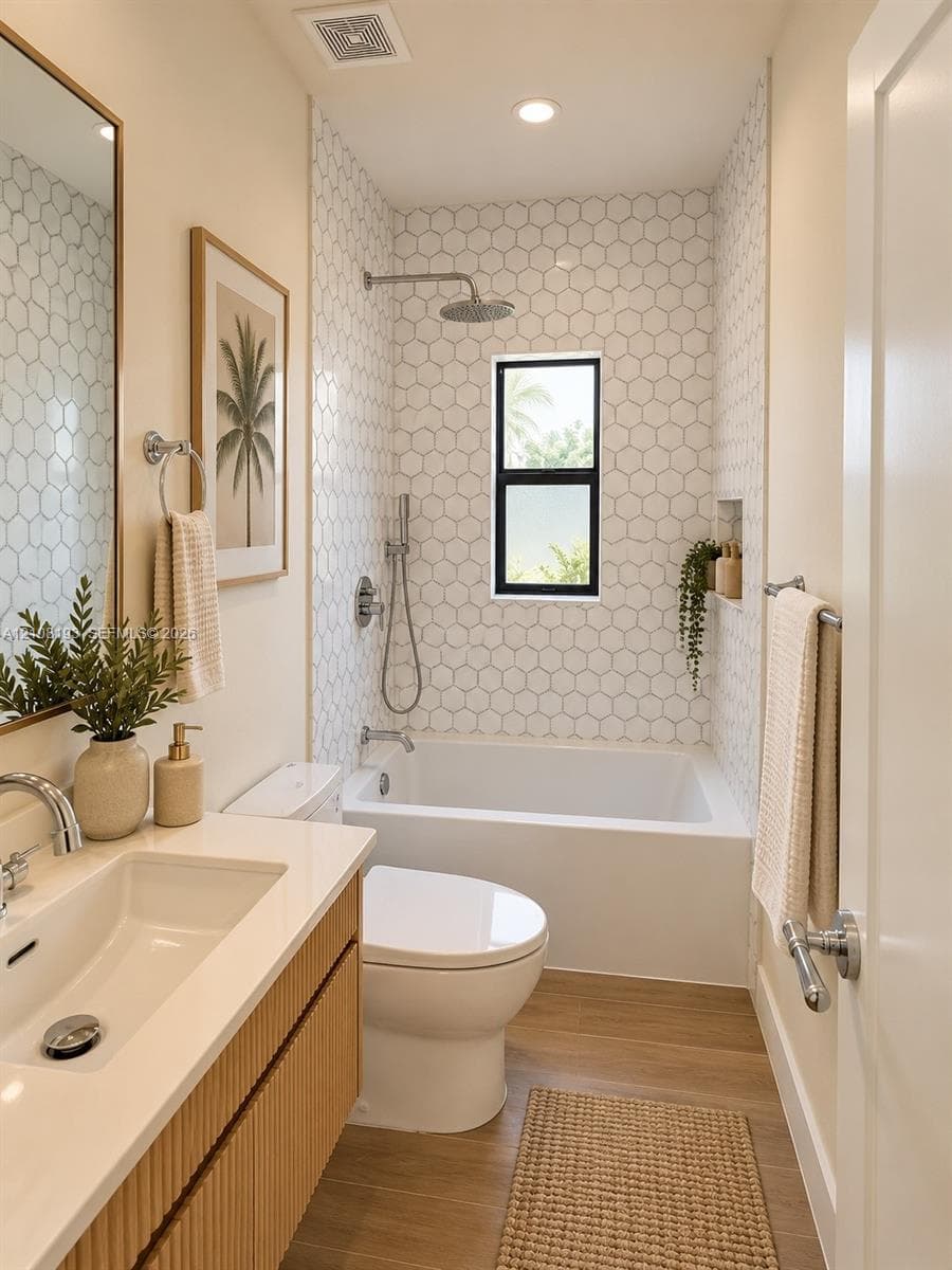 Bathroom featuring a wood-finish vanity with a white countertop and integrated sink, hexagon-patterned wall tile, a recessed shower niche, and a combination tub and shower with a rainfall showerhead