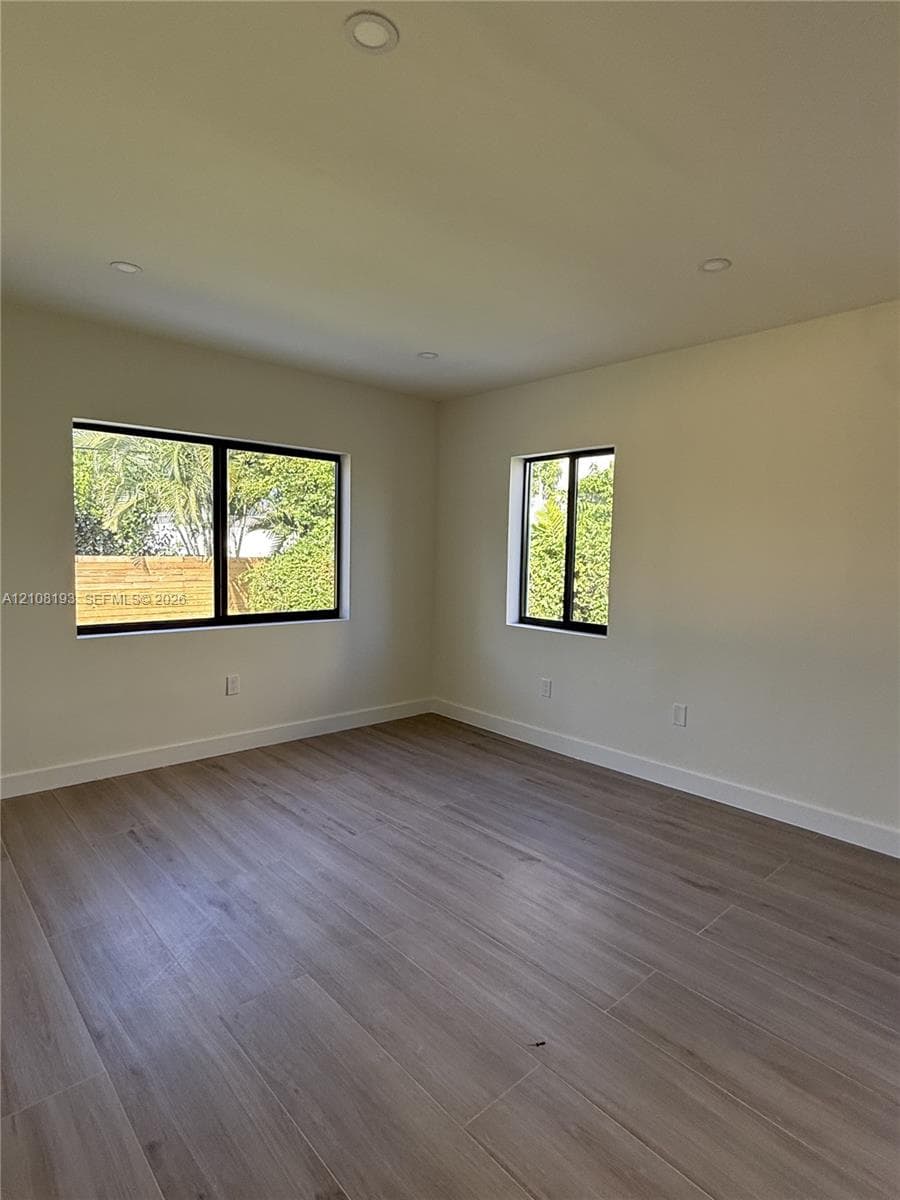 Interior space featuring wood-finish flooring, recessed lighting, and windows with black frames
