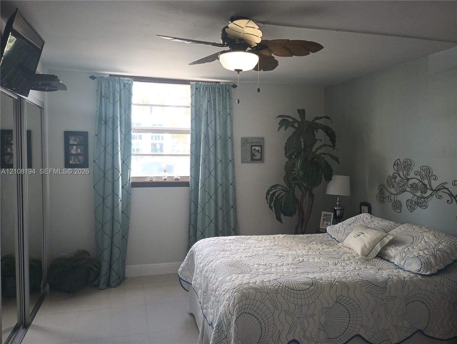 Light-filled room featuring tile flooring, sliding mirror-door closet, and a ceiling fan with integrated lighting