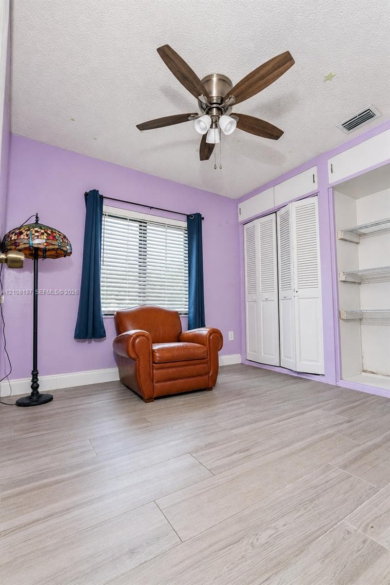 Wood-finish flooring, ceiling fan with integrated lighting, dual bifold closet doors, and open shelving