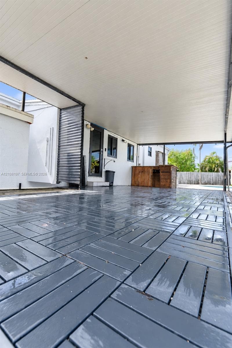 Covered patio featuring gray interlocking deck tiles, white ceiling paneling, and a built-in wooden structure