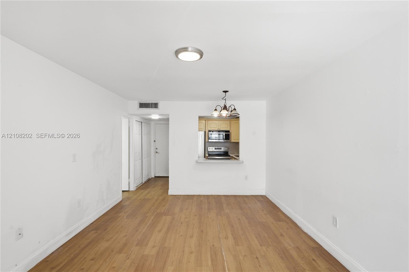 Interior space featuring wood-finish flooring, recessed ceiling lighting, a pass-through opening to the kitchen, and a kitchen featuring stainless steel appliances