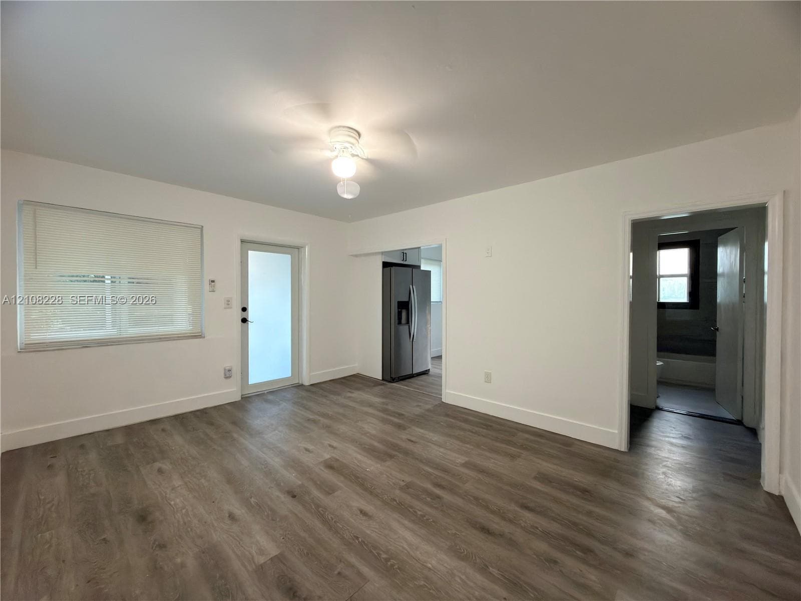 Interior space featuring wood-finish flooring, a neutral color palette, a ceiling-mounted light fixture, and an exterior door with glass paneling