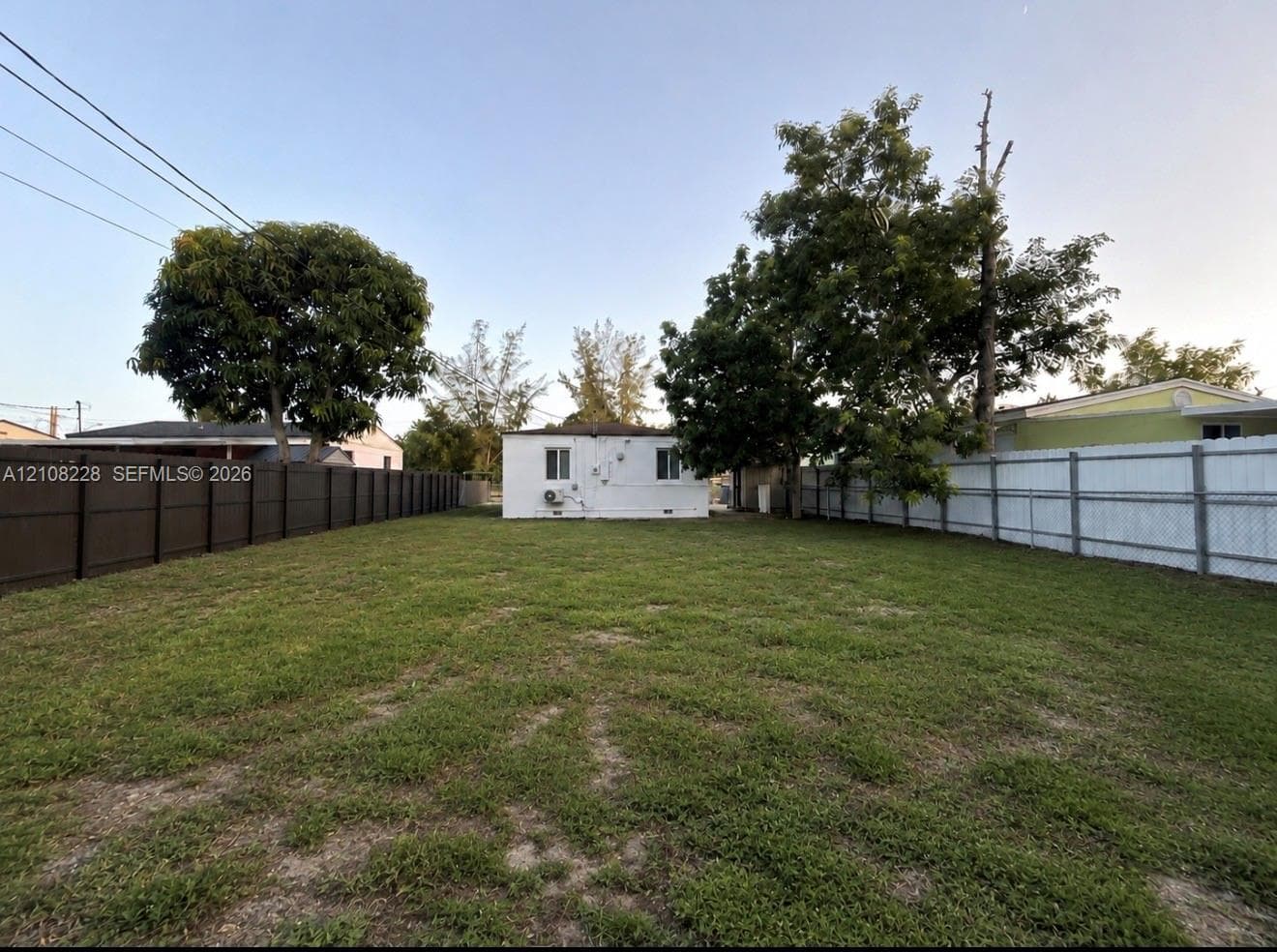 Expansive backyard featuring a large grass lawn, mature trees, and perimeter fencing