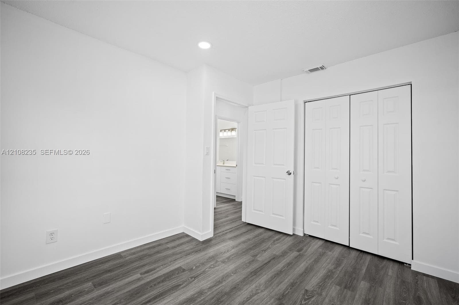 Wood-finish flooring, recessed lighting, and white bi-fold closet doors
