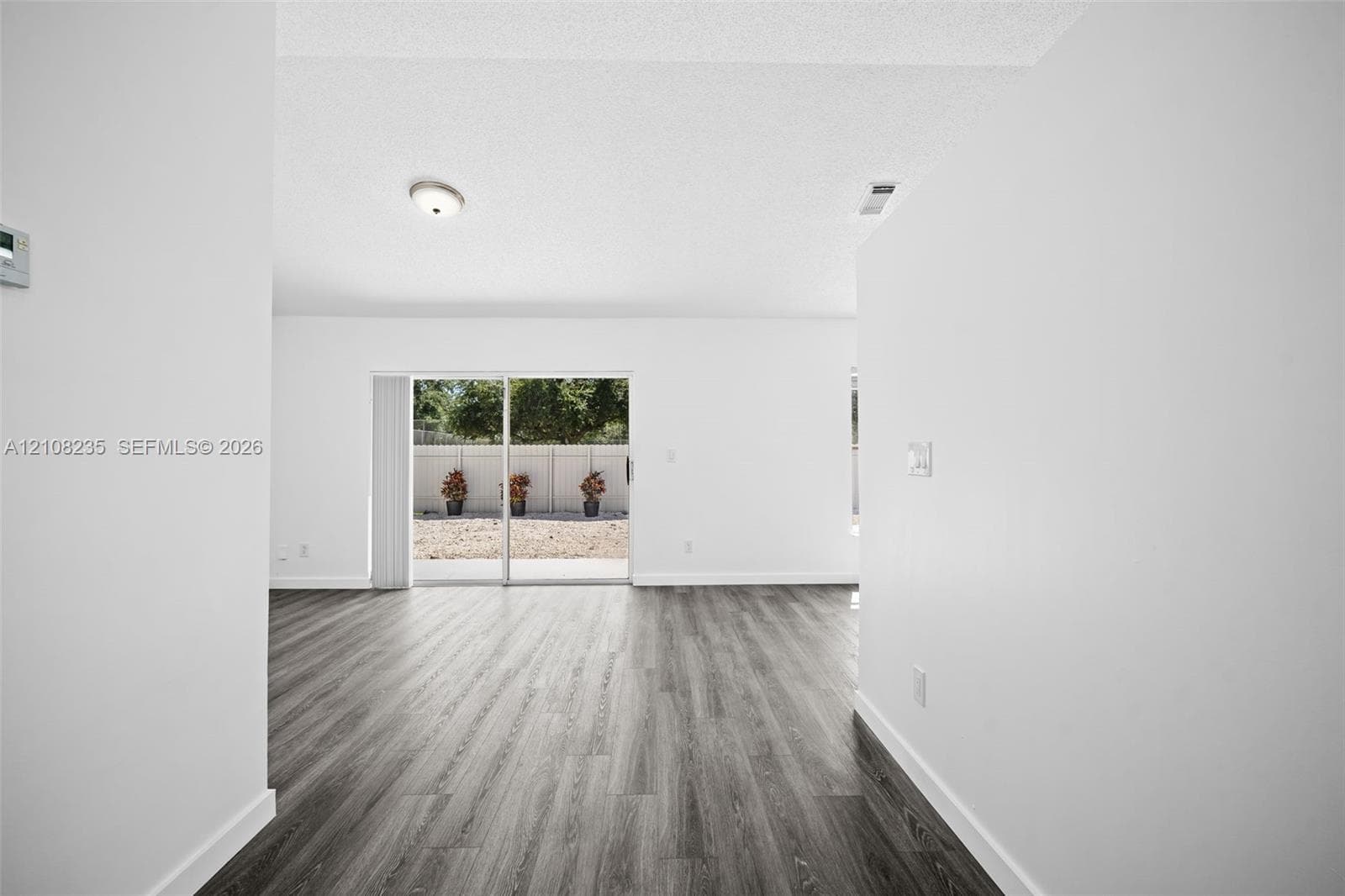 Wood-finish flooring, white walls, and glass sliding door providing exterior access to a fenced rear area