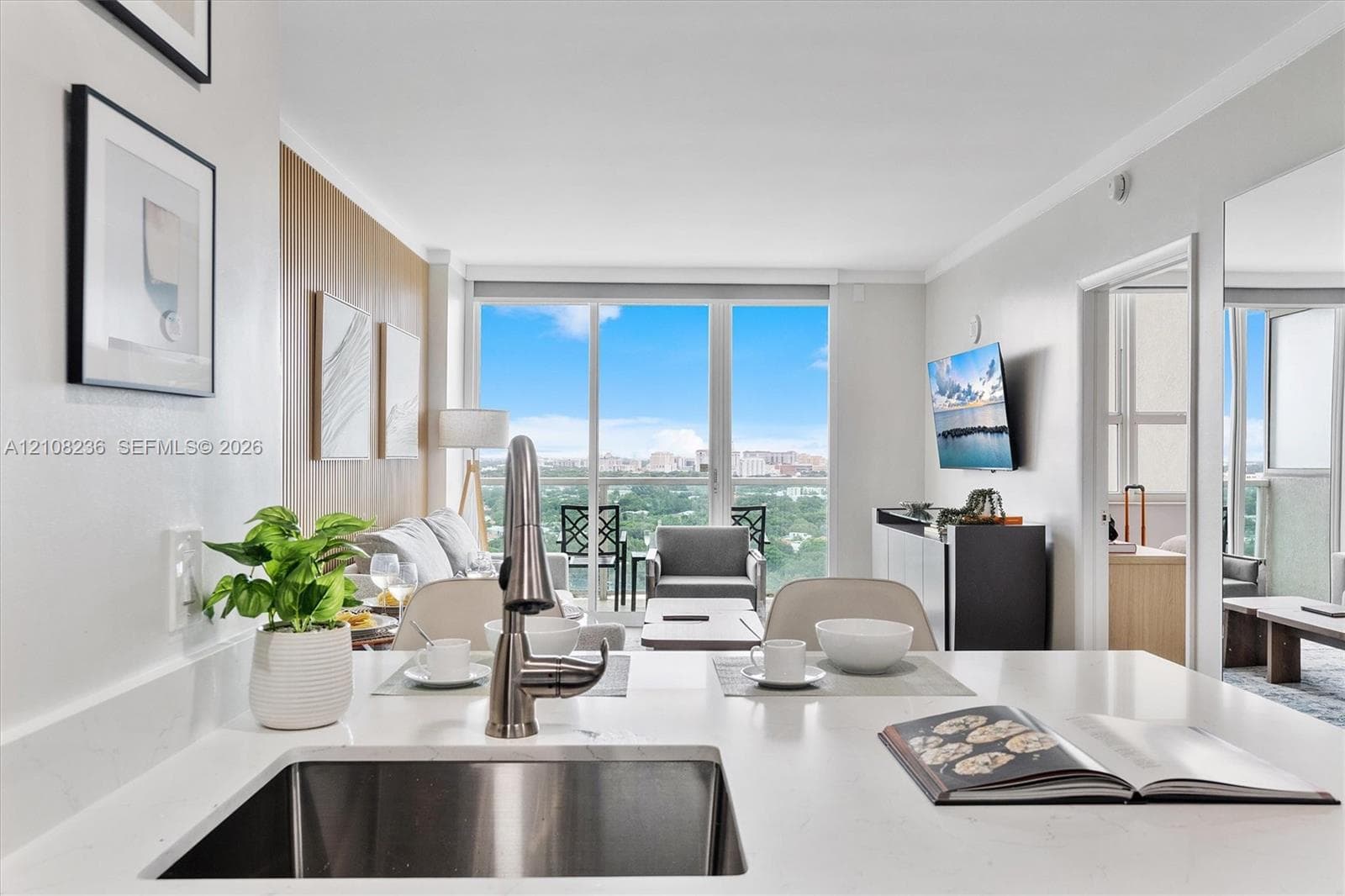 Kitchen featuring a white quartz countertop, undermount stainless steel sink, and high-arc faucet, accompanied by floor-to-ceiling windows and a private balcony