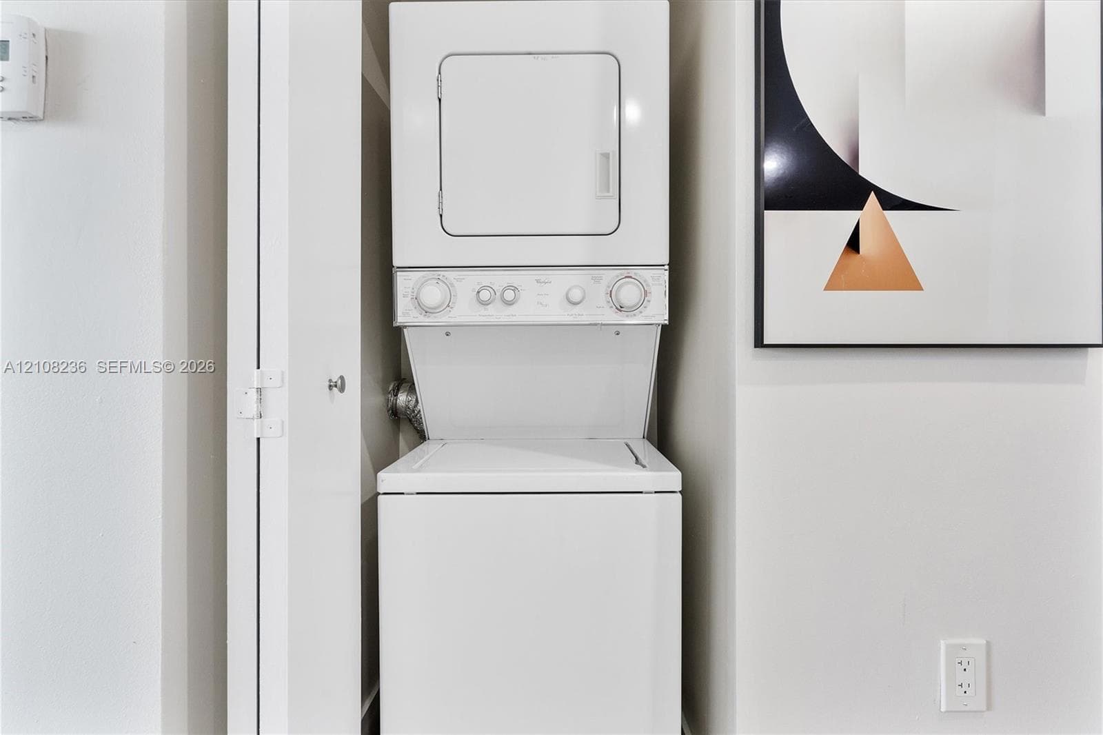 Stacked white laundry unit housed within a built-in closet
