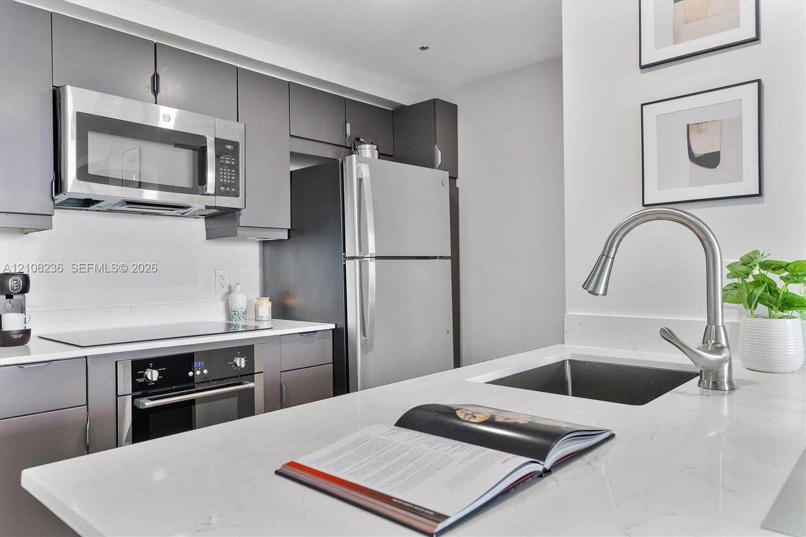 Kitchen featuring flat-panel cabinetry, quartz countertops, stainless steel appliances, and a gooseneck faucet with an undermount sink