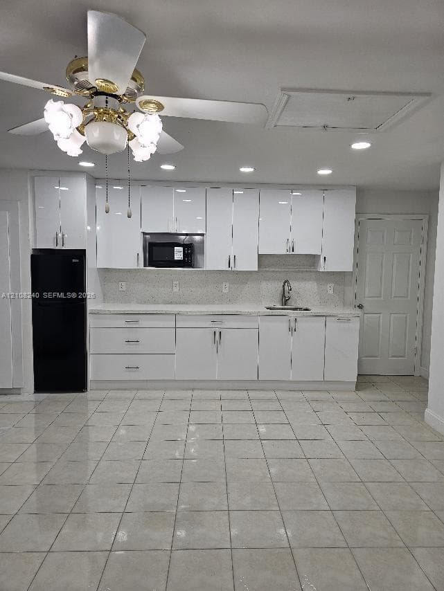Glossy white cabinetry with modern hardware, stone-finish countertops, recessed ceiling lighting, tiled flooring, and a multi-light ceiling fan