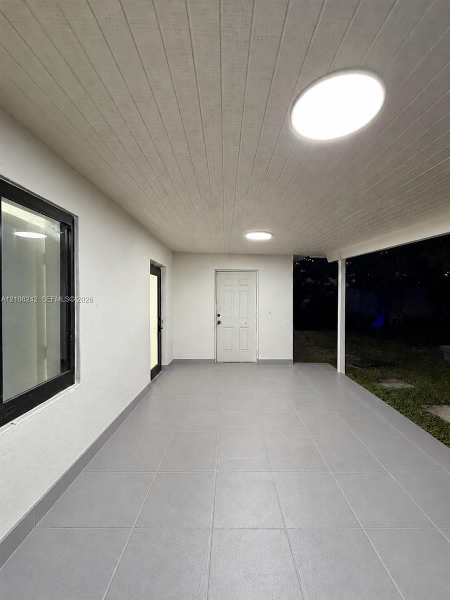 Covered patio featuring large-format grey tile flooring, tongue-and-groove ceiling paneling, and flush-mount LED lighting