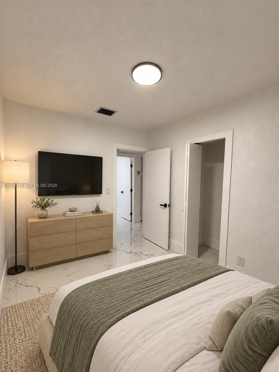 Neutral-toned interior featuring large-format stone-finish tile flooring with veining, round flush-mount ceiling lighting, and solid-core doors with matte black hardware