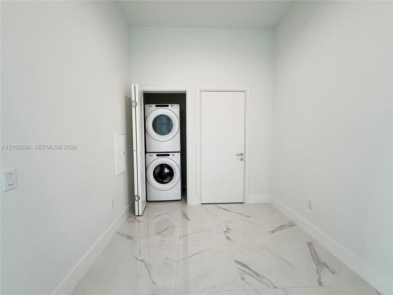 Dedicated utility space featuring stone-finish floor tile, a recessed laundry closet, and a stackable washer and dryer unit