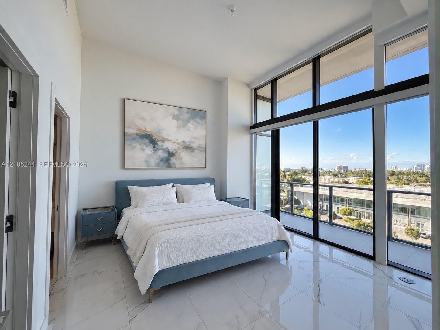 High ceilings featuring floor-to-ceiling windows with balcony access and light-toned, vein-patterned tile flooring