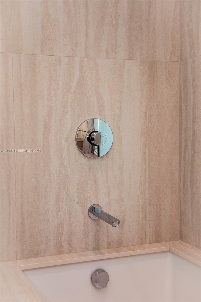 Large-format stone tile wall surround, polished chrome single-handle pressure balance valve, and integrated chrome tub spout