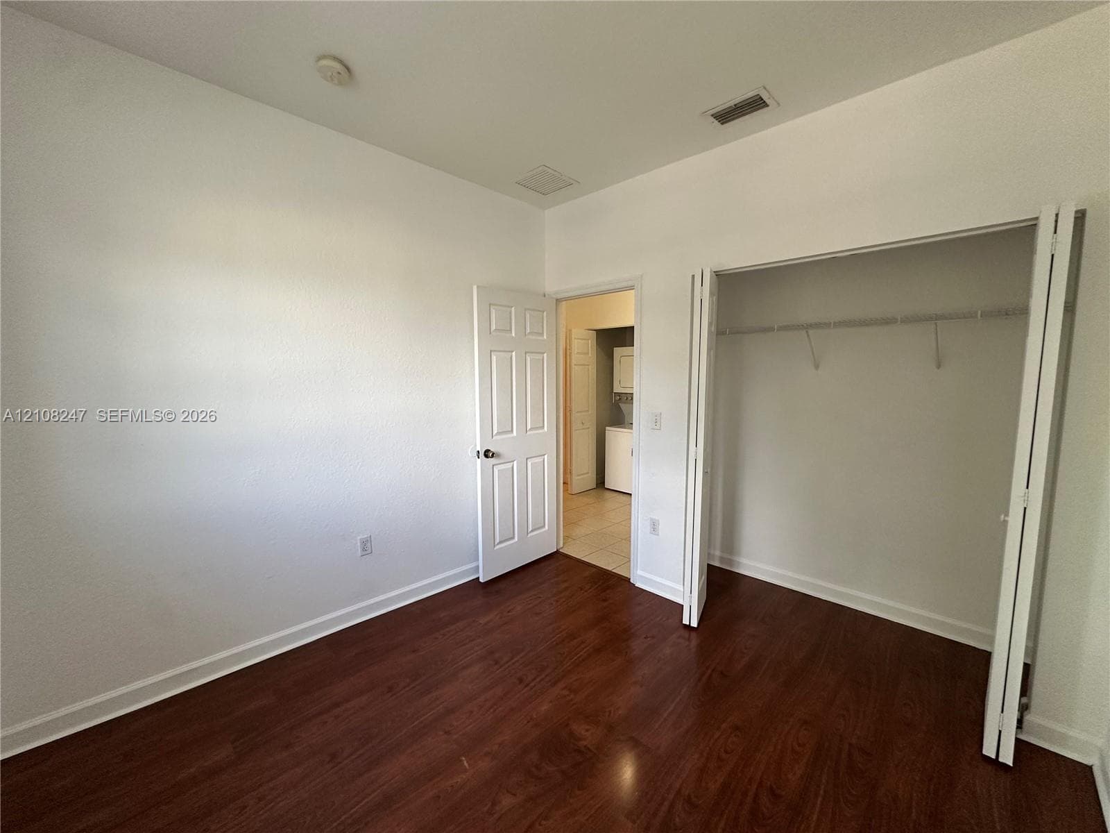 Interior space featuring wood-finish flooring, a bi-fold door closet with built-in shelving, and a six-panel interior door