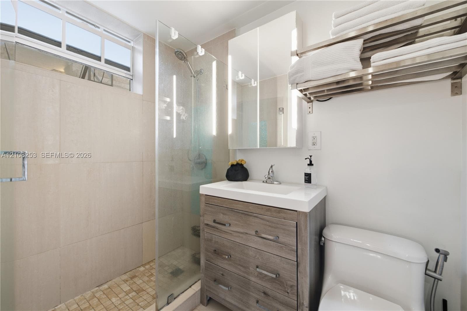Walk-in shower featuring floor-to-ceiling tile, frameless glass enclosure, and a handheld shower head