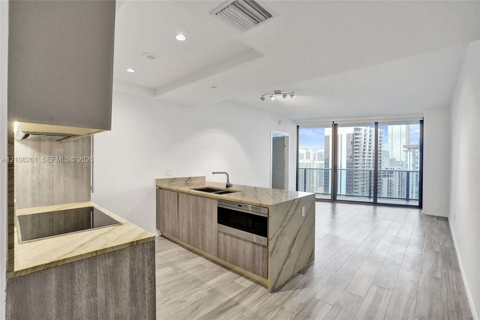 Kitchen featuring stone countertops with waterfall edge, wood-finish cabinetry, built-in cooktop, integrated microwave, and wood-finish flooring