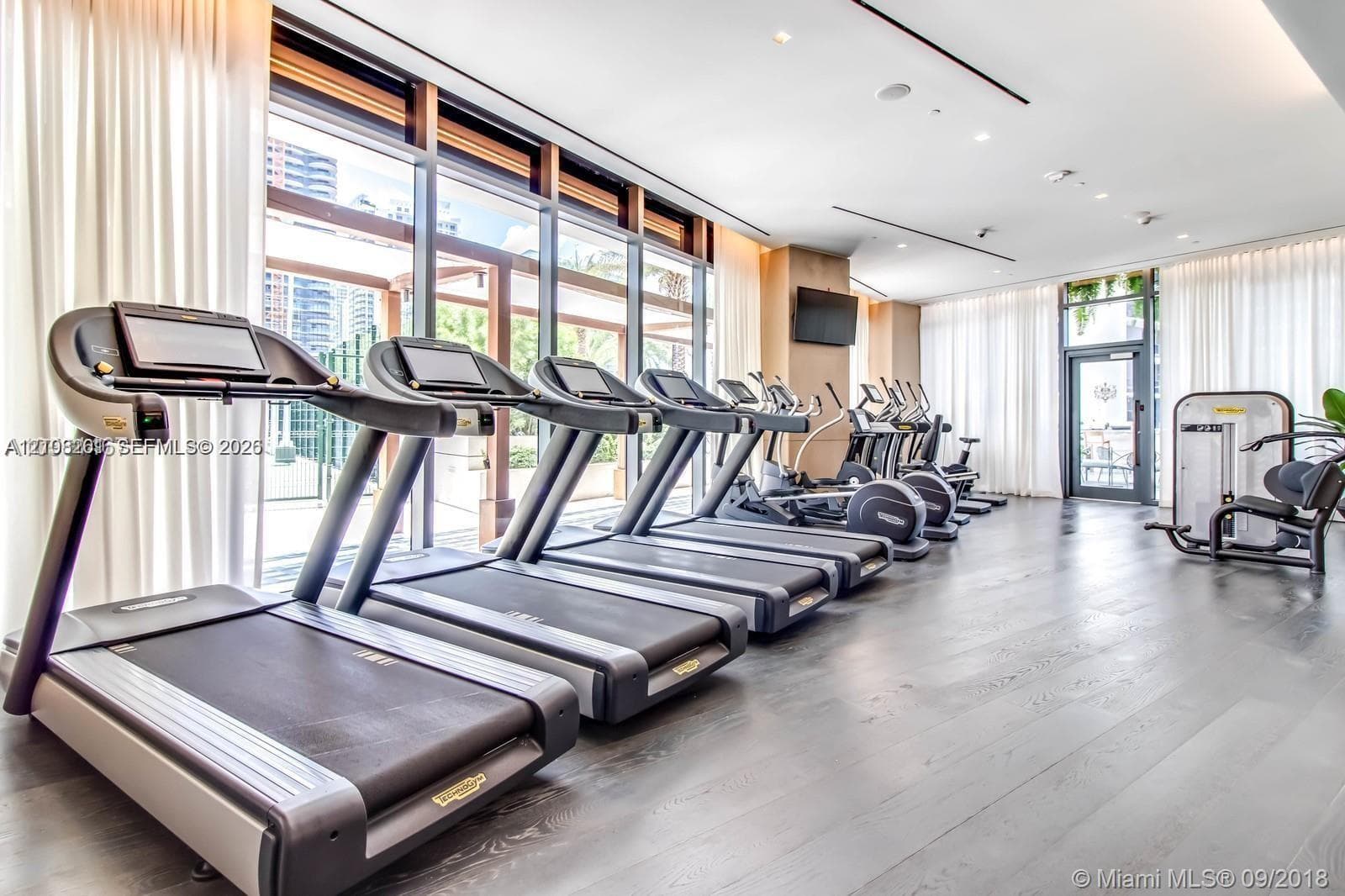 Fitness center featuring wood-finish flooring, floor-to-ceiling windows, and recessed ceiling lighting