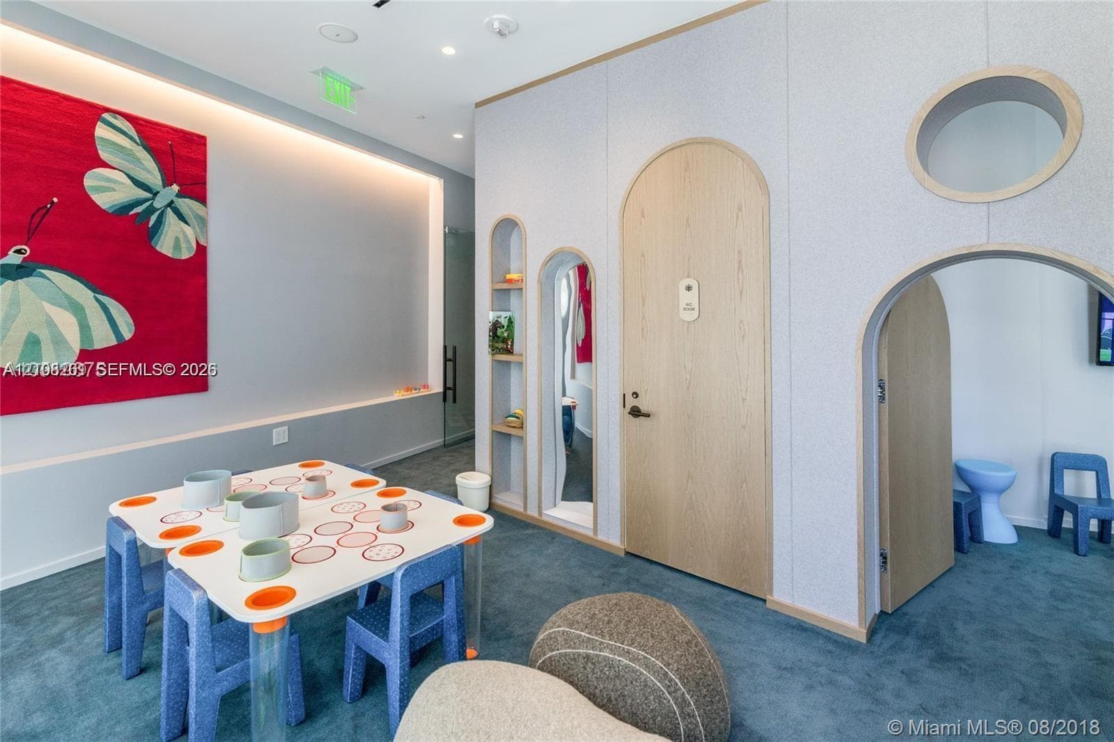 Interior space featuring custom wall paneling, arched entryways, built-in recessed shelving, integrated cove lighting, and carpeted flooring