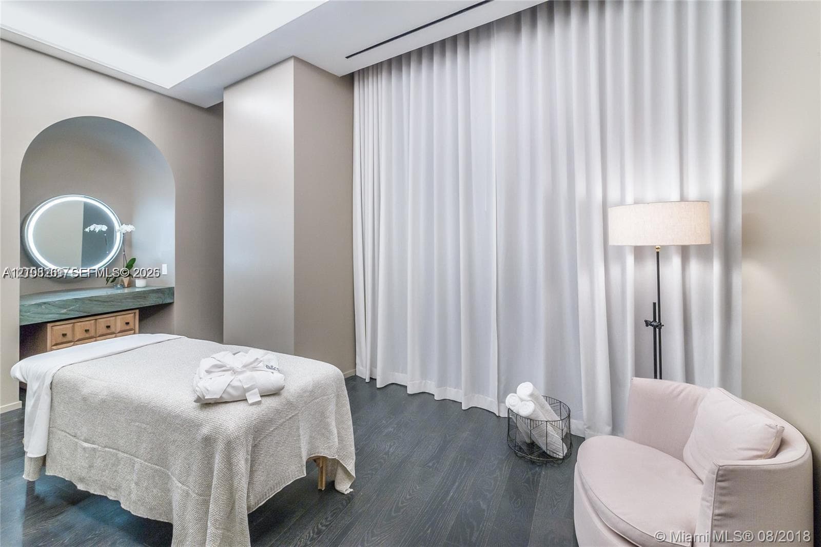 Arched recessed alcove featuring a built-in vanity with stone countertop, wood-finish cabinetry, and a circular wall-mounted LED mirror