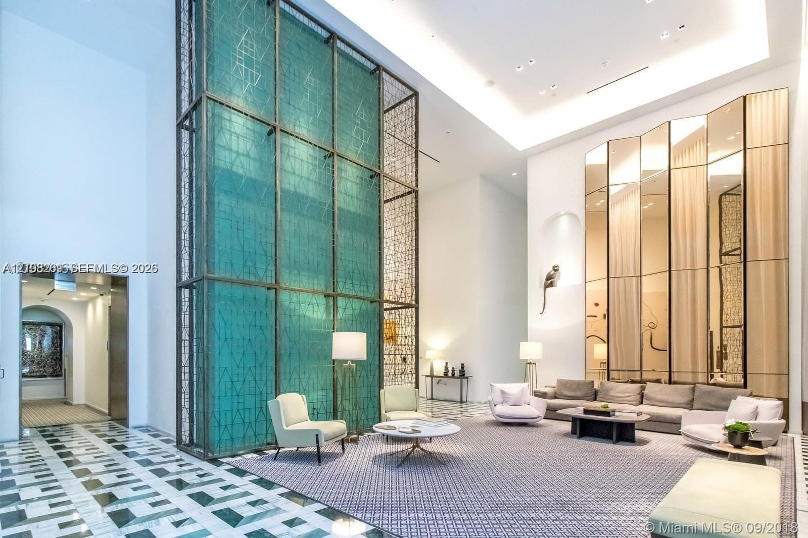 Double-height ceilings, floor-to-ceiling geometric metal screen feature, expansive mirrored wall panels, recessed cove lighting, and patterned stone flooring