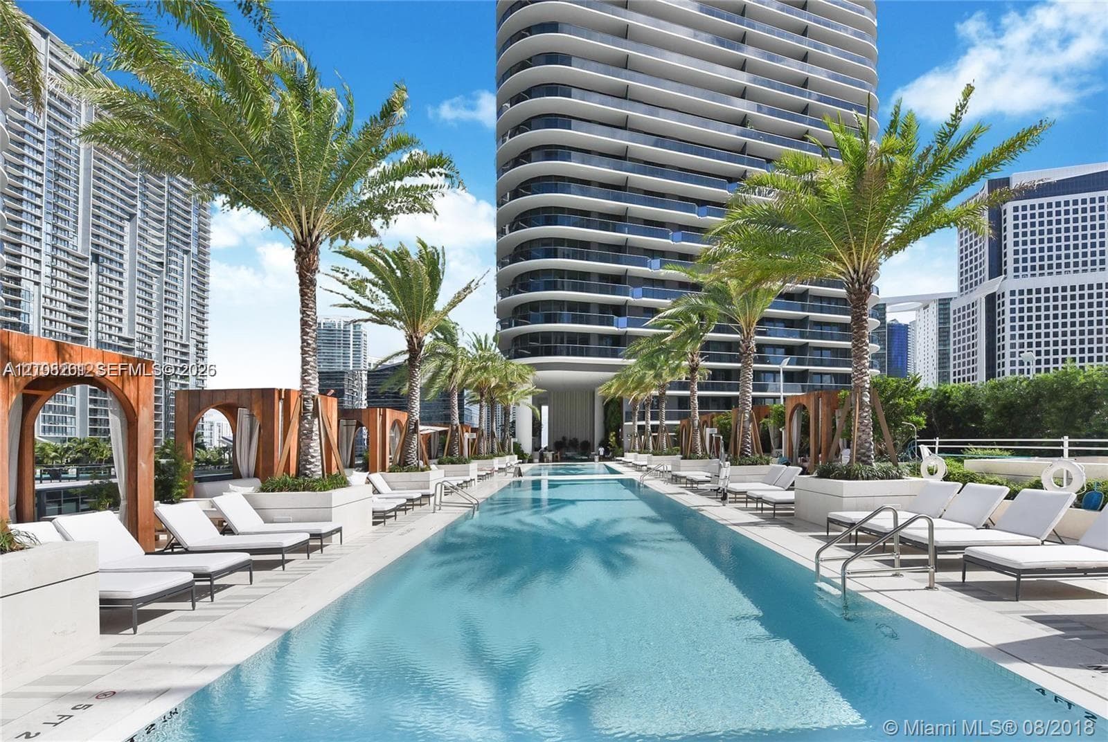 Expansive lap pool with tile surround, raised concrete planters, and integrated wooden cabanas