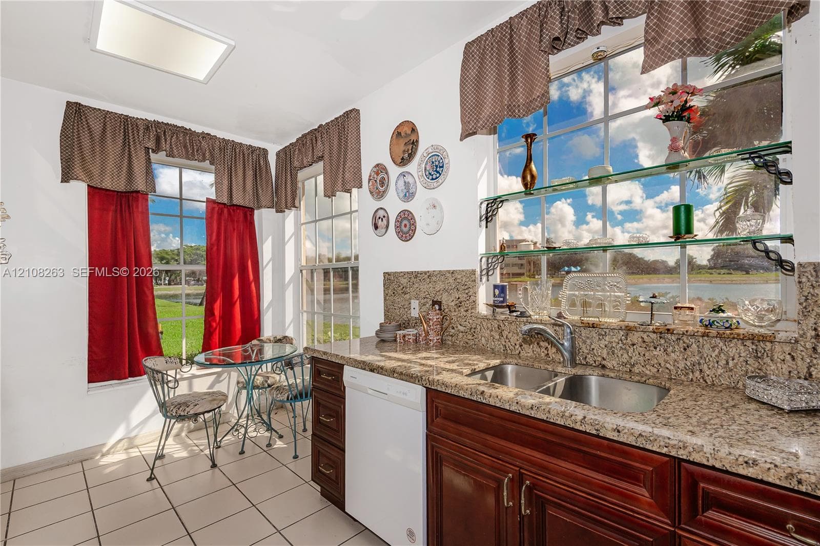 Kitchen featuring stone-finish countertops, stainless steel dual-basin undermount sink, dark-finish cabinetry, tile flooring, and multiple large windows