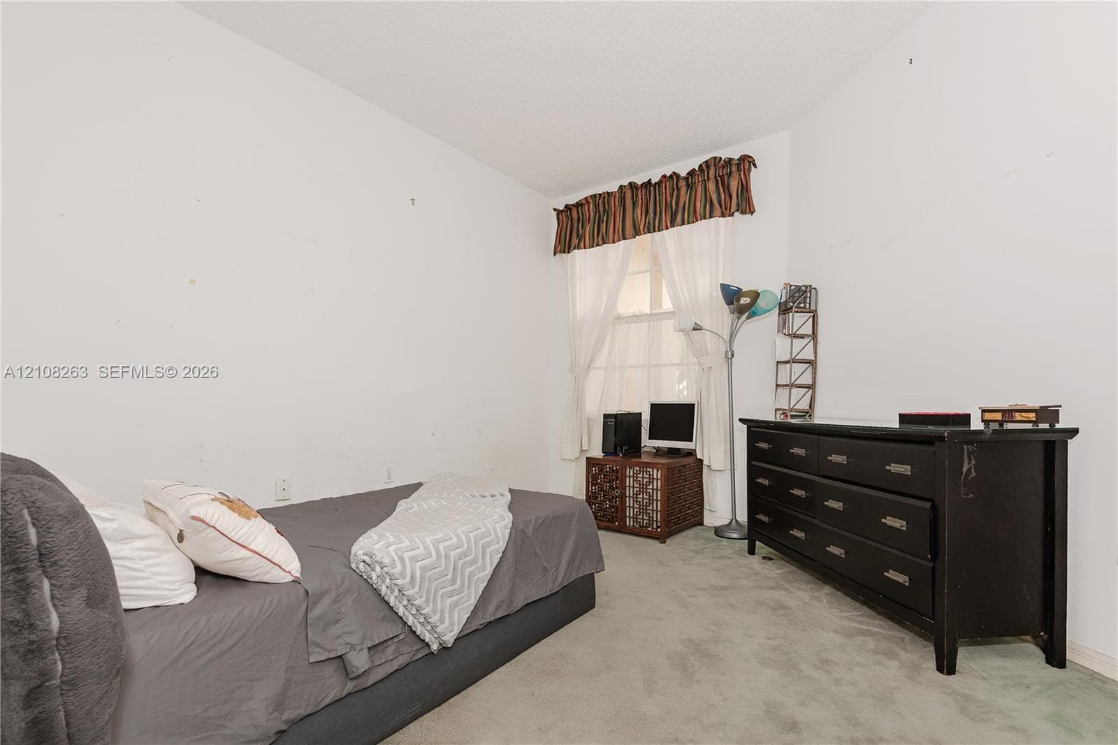 Interior room featuring neutral wall finishes, wall-to-wall carpeting, and a window with a fabric valance
