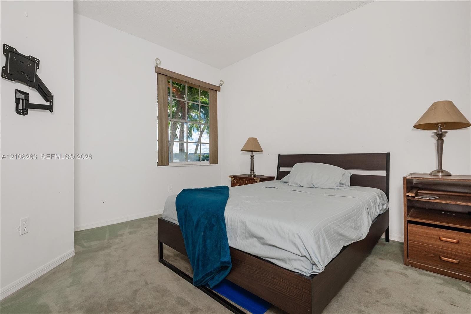 Bedroom interior featuring wall-to-wall carpeting and a multi-pane window with wood-finish blinds