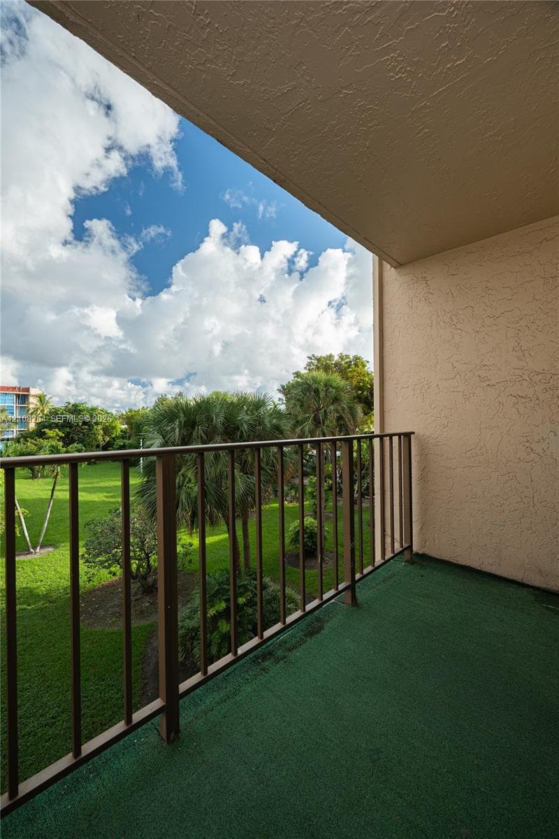 Covered balcony featuring a metal railing and textured stucco wall