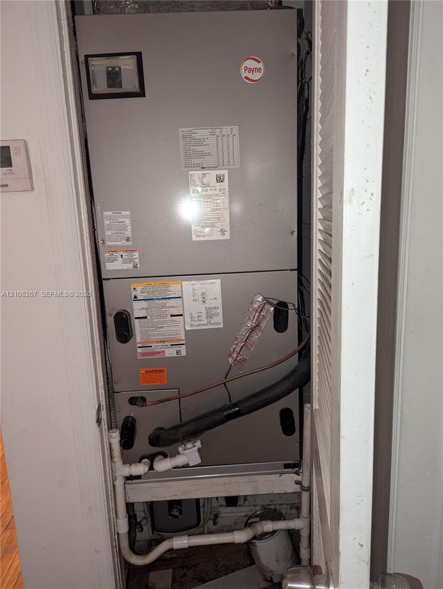 Payne furnace unit featuring a metal enclosure with built-in plumbing connections and a mounted digital thermostat