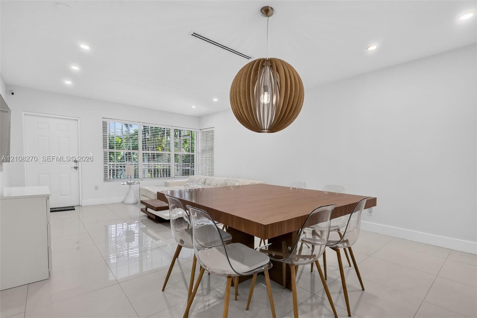 Large-format neutral tile flooring, recessed ceiling lighting, and a spherical wood-slat pendant fixture
