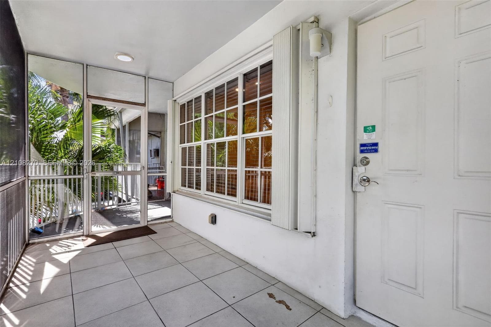 Screened-in porch featuring tiled flooring, a multi-pane window with aluminum framing, and an exterior door