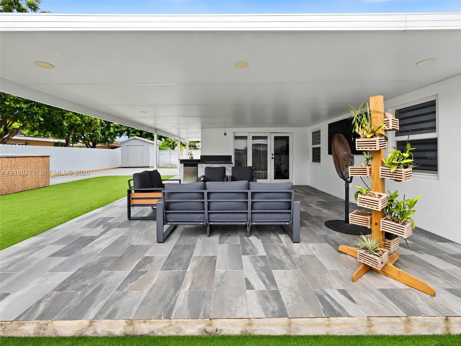 Covered patio featuring large-format stone-finish tile flooring, recessed lighting, and a built-in outdoor kitchen counter