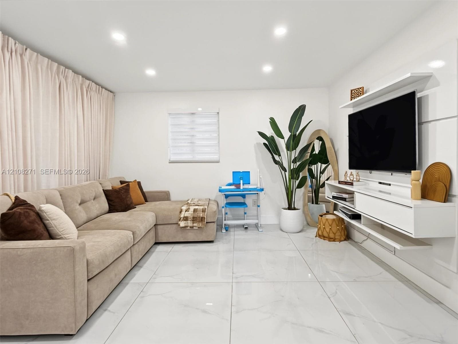 Living space featuring large-format tile flooring, recessed lighting, and a custom white wall-mounted media console