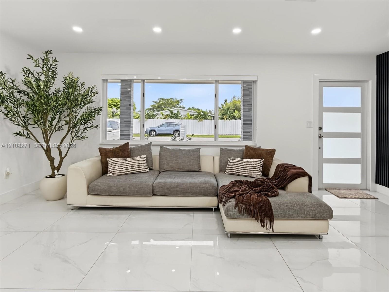 Large-format porcelain tile flooring, recessed lighting, and a modern entry door with horizontal frosted glass panels