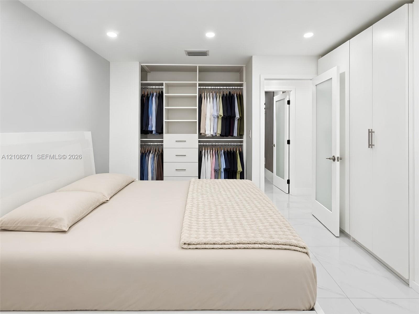 Built-in wardrobe system with integrated shelving and drawers, floor-to-ceiling cabinetry, recessed lighting, and large-format tile flooring