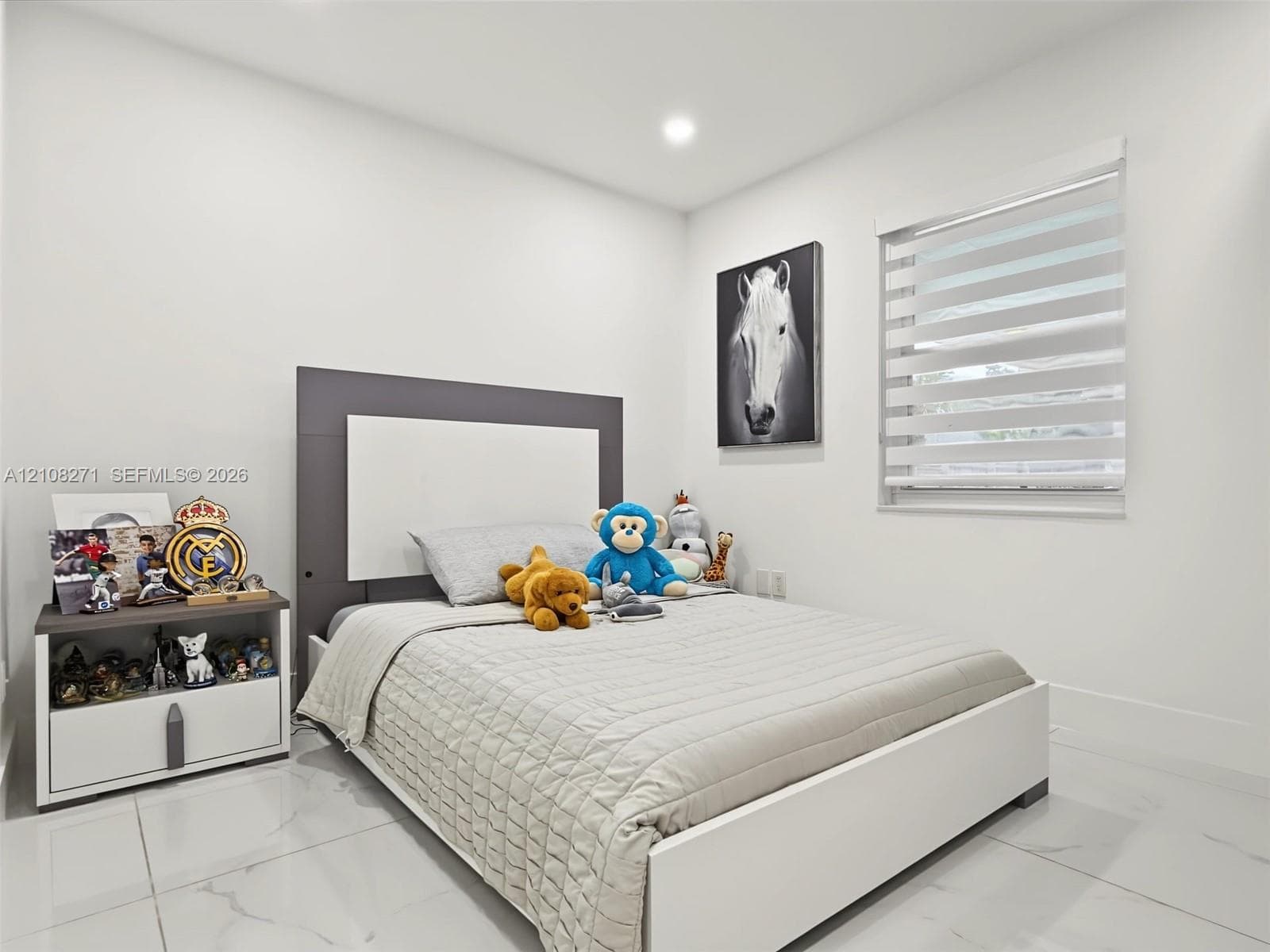 Neutral-toned interior featuring large-format tile flooring, recessed ceiling lighting, and a dual-shade roller window treatment