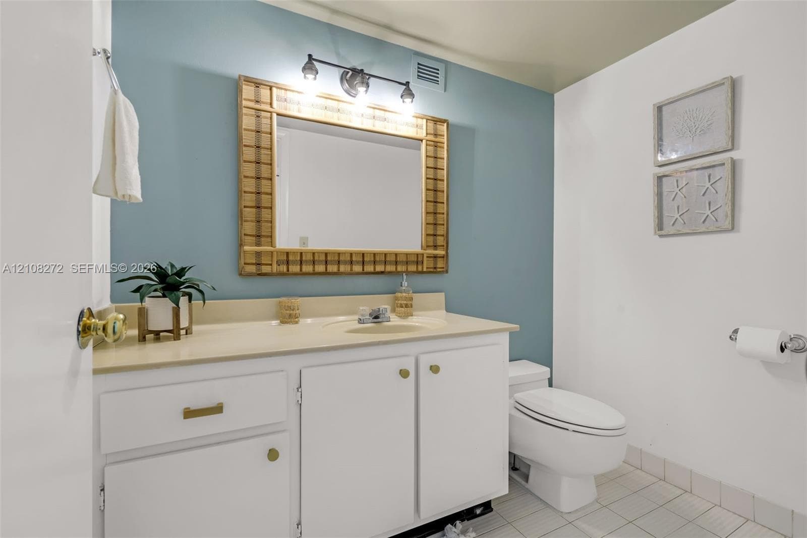 Bathroom featuring a white vanity cabinet with an integrated sink, neutral countertop, wall-mounted light fixture, and tile flooring