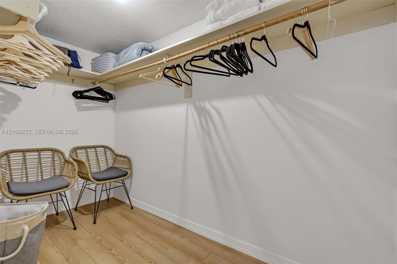Walk-in closet featuring wood-finish flooring and integrated wall-to-wall shelving with a hanging rod