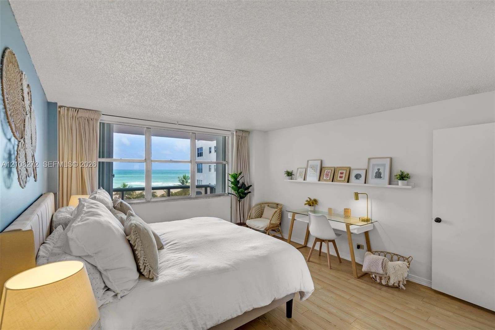 Large window featuring ocean scenery, wood-finish flooring, accent wall, and built-in wall shelving
