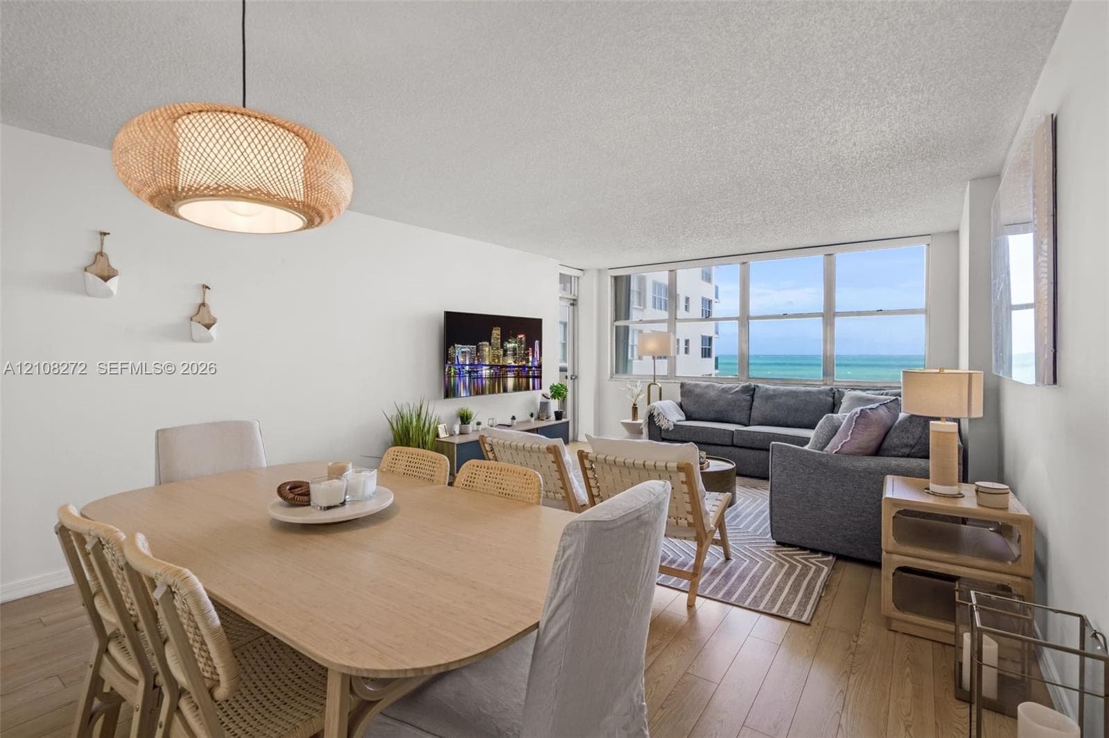 Open-concept living space featuring wood-finish flooring, floor-to-ceiling windows, and a woven pendant light fixture
