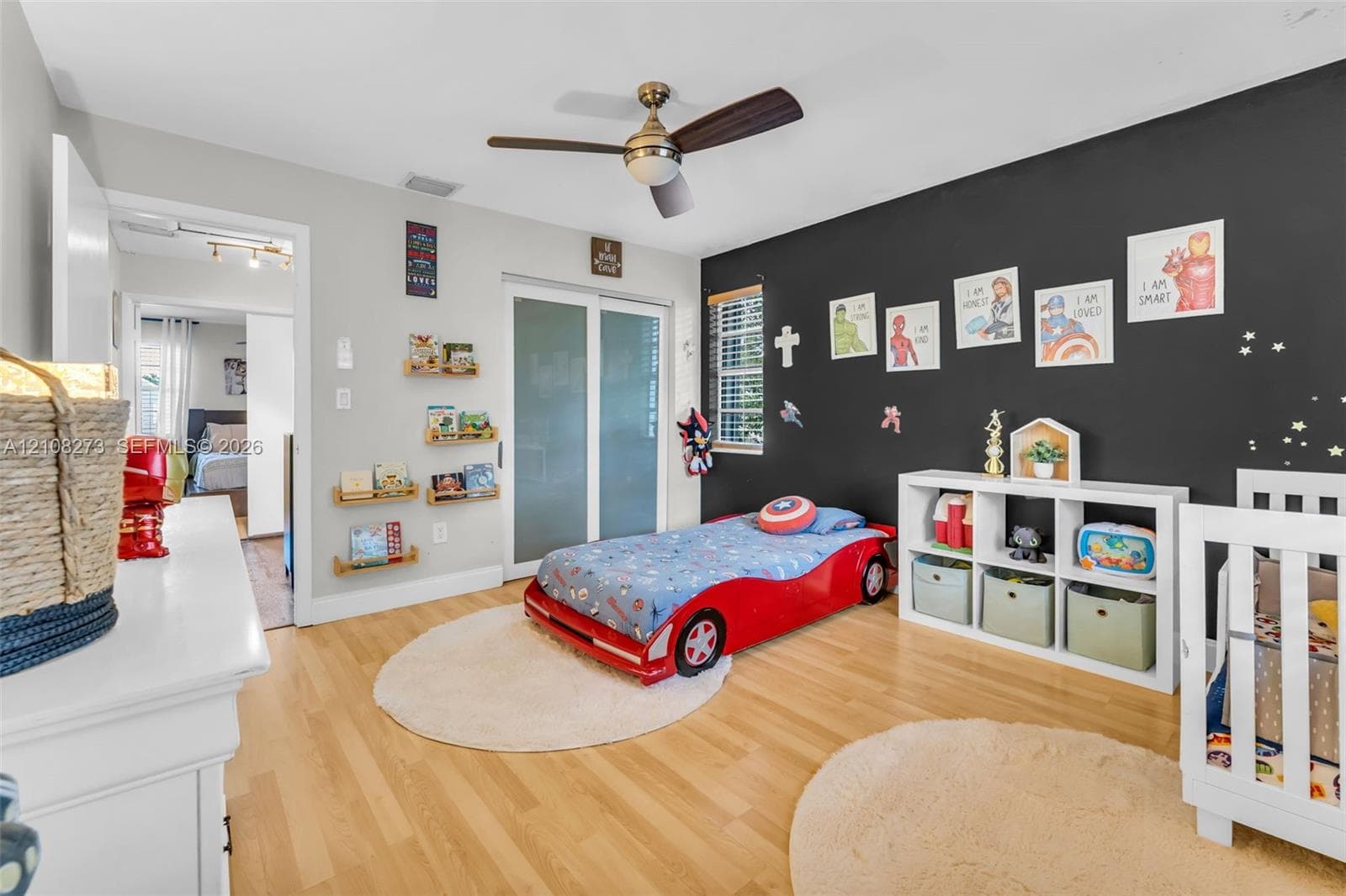 Wood-finish flooring, brushed metal ceiling fan with integrated light fixture, contrast accent wall, and sliding glass closet doors