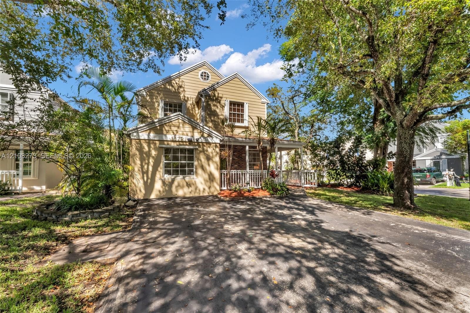 Two-story residence featuring horizontal lap siding, a front covered porch with railing, multi-pane windows, and an asphalt driveway