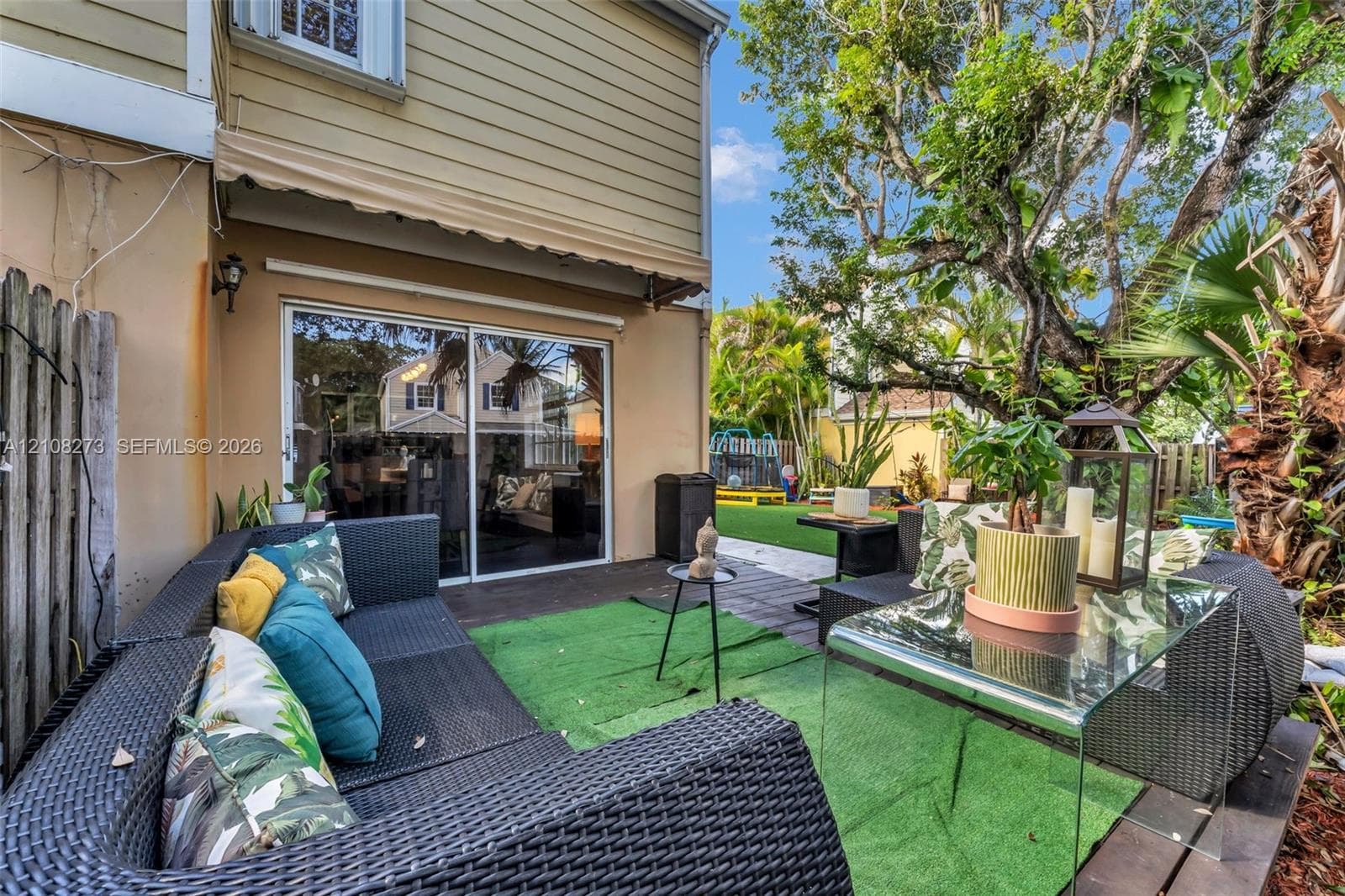 Rear patio featuring dark-tone wood-finish decking, retractable fabric awning, and sliding glass doors