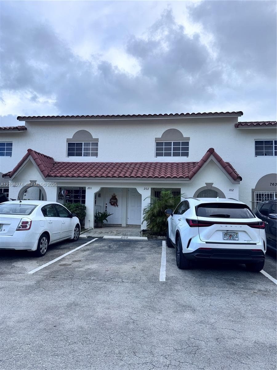 Two-story stucco exterior featuring, arched entryway accents, and dedicated surface parking